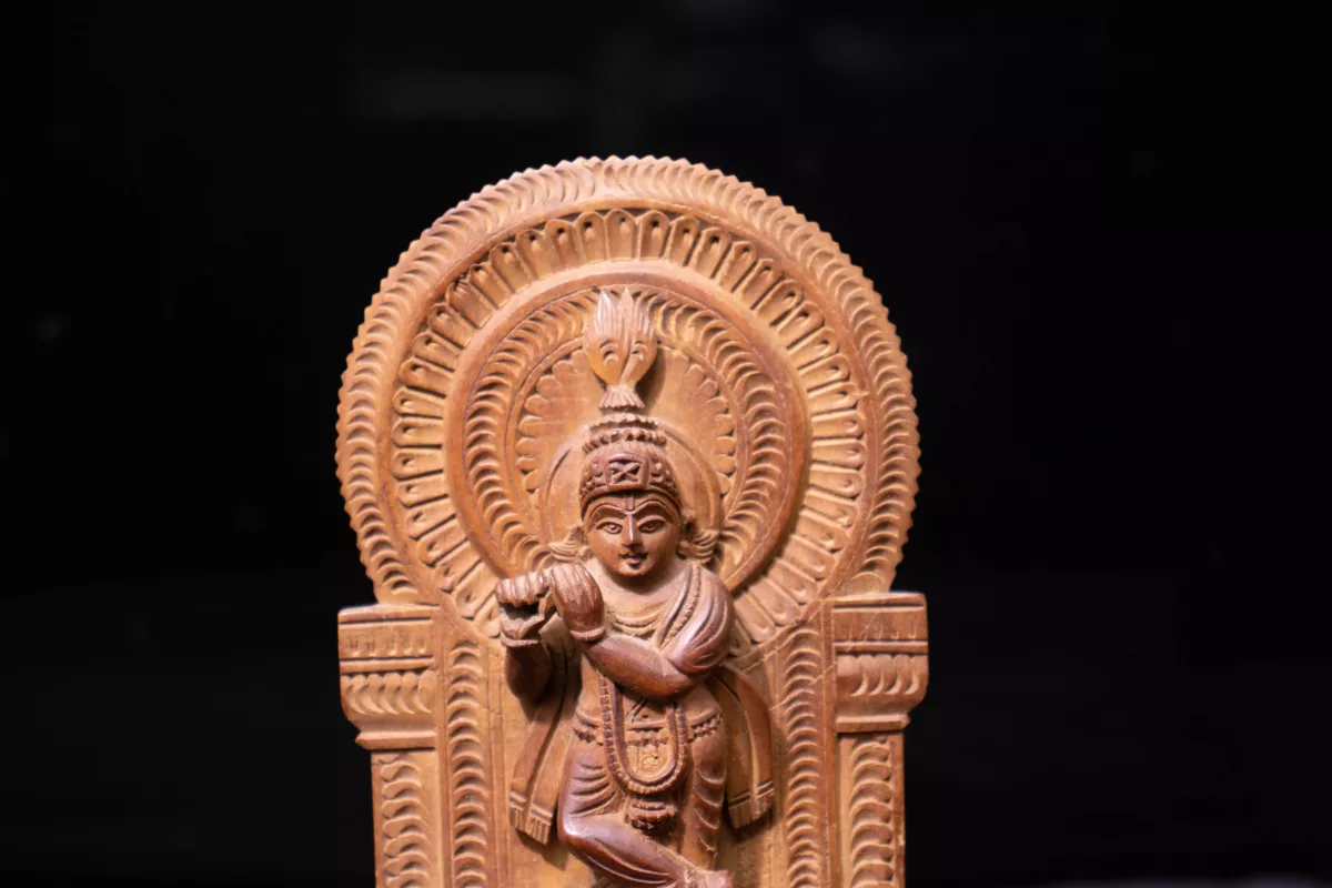 Wooden sculpture of Krishna holding flute with both hand and a crossed leg