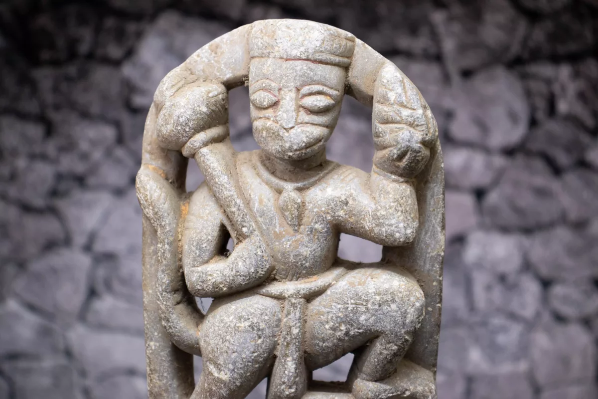 Stone sculpture of hanuman with his gadha sitting on one knee