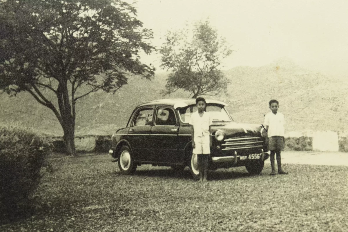 Vintage photograph of two boys standing with ambassador car